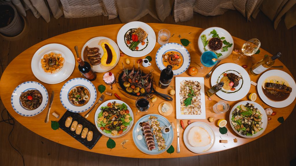Top view of an elegant dining table set with diverse gourmet dishes and wine bottles.